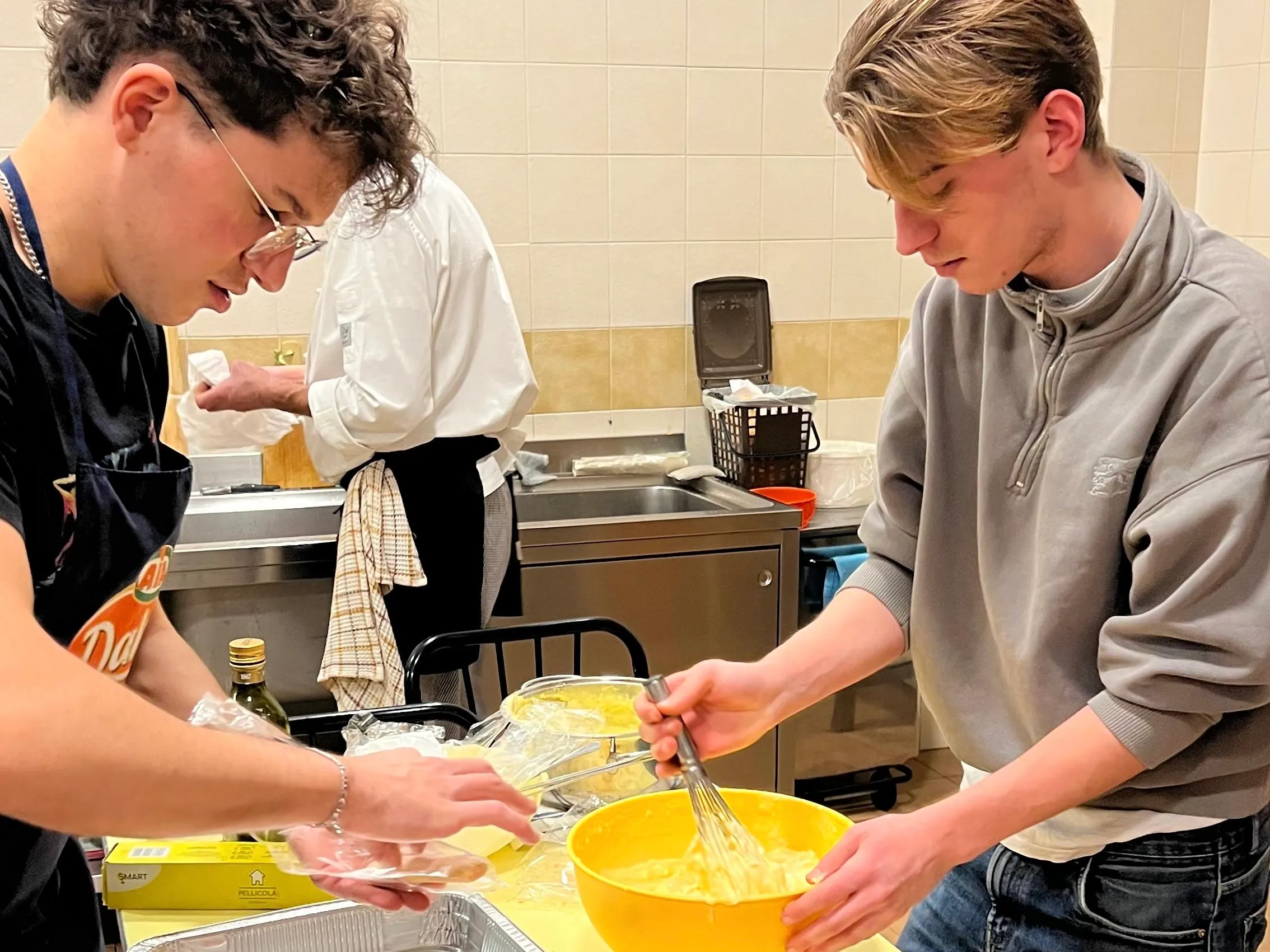 Studenti del Pensionato Bertoni che cucinano insieme nella cucina della residenza universitaria