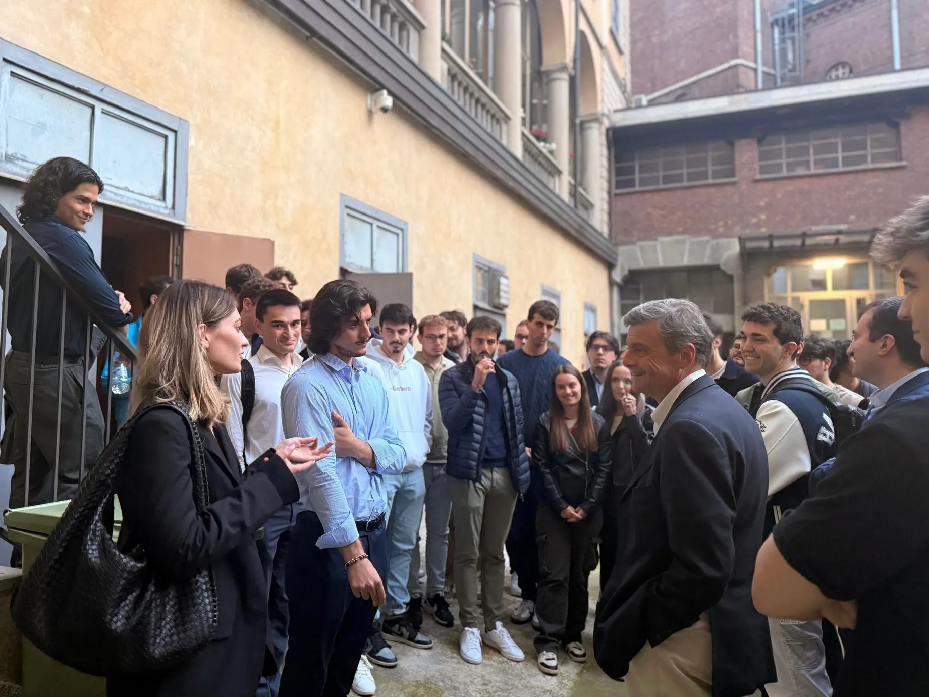 Studenti universitari che dialogano con un ospite nel cortile del Pensionato Bertoni