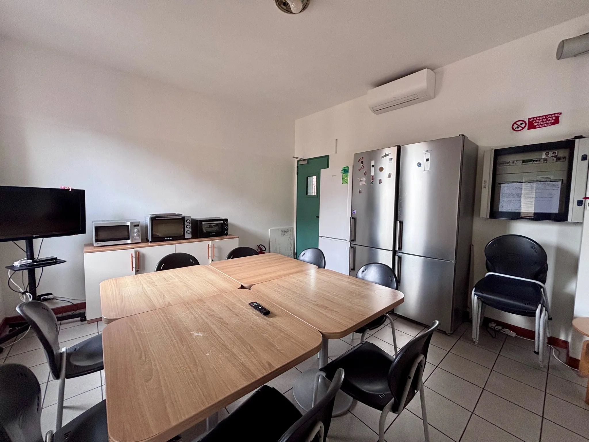 Fully equipped student kitchen with table, refrigerators, microwaves and TV