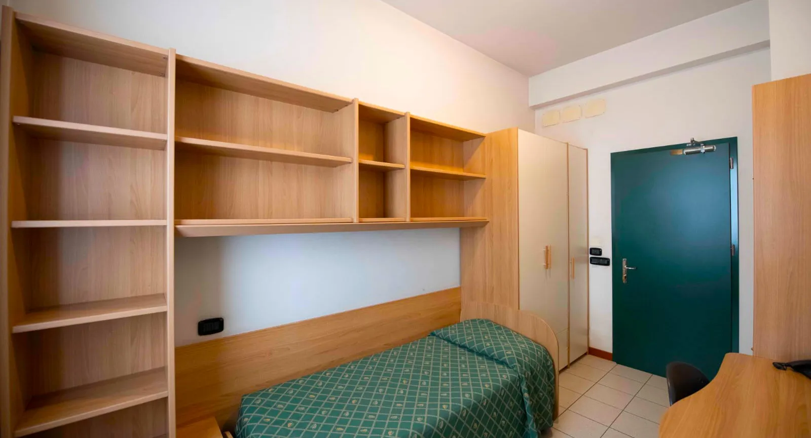 Furnished room with wardrobe, bookshelf and single bed at the student residence