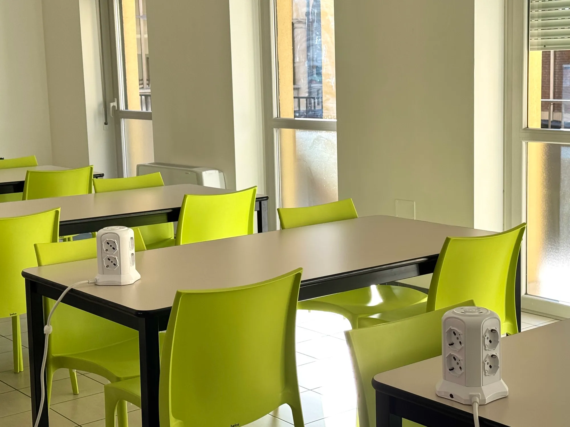 Study room at the student residence with natural light and green chairs